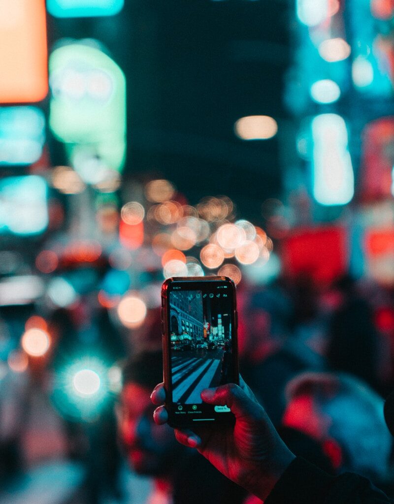 person taking photo of city during night time