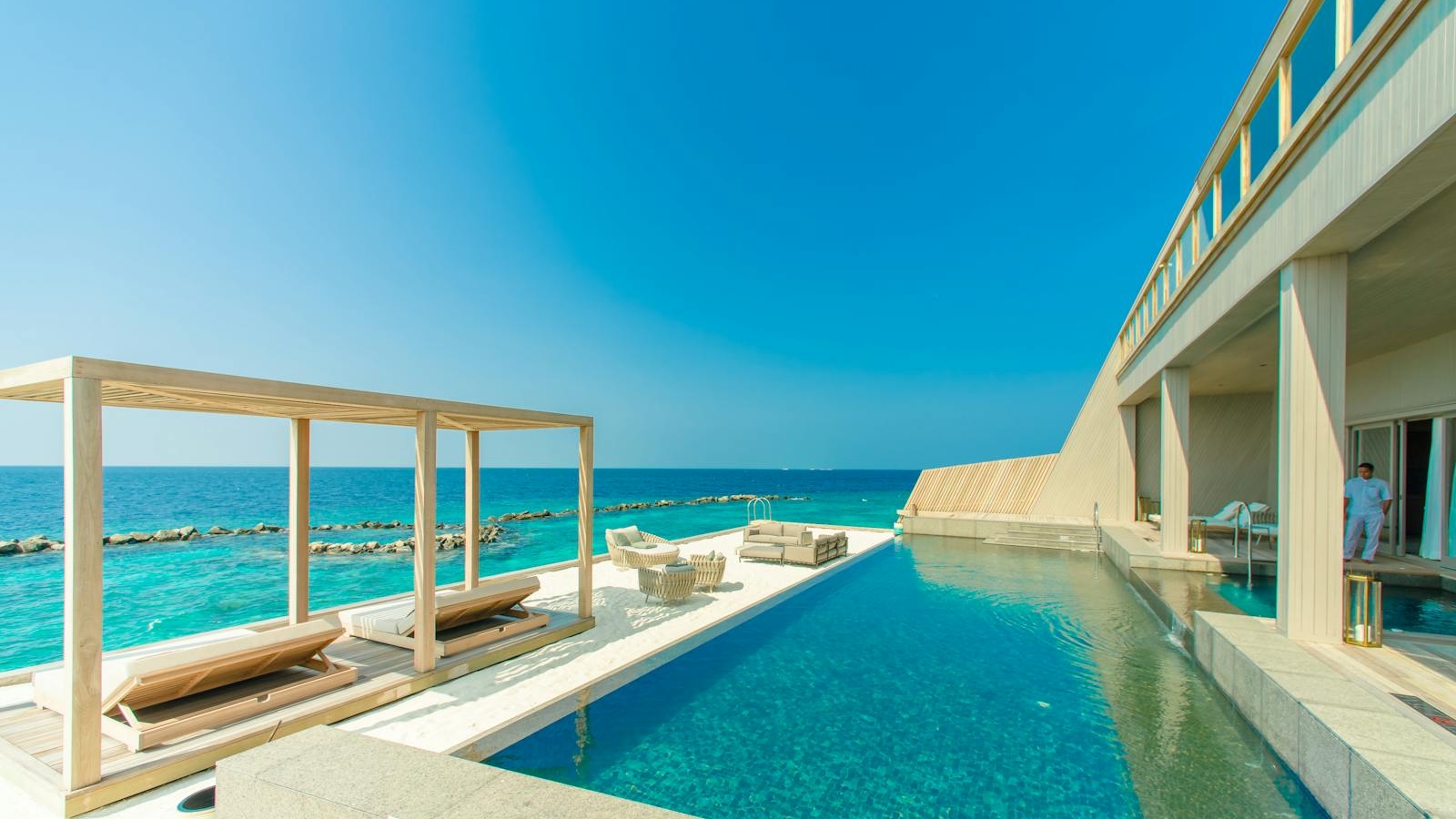 Stunning view of a luxury resort in Maldives with an infinity pool overlooking the ocean.