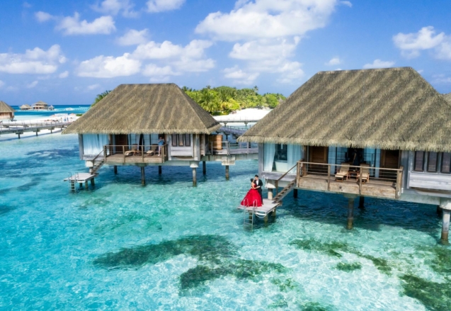 A scenic view of overwater bungalows and a couple enjoying a tropical paradise in the Maldives.