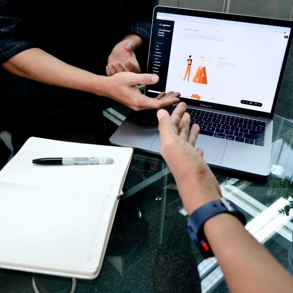 person using macbook pro on white table