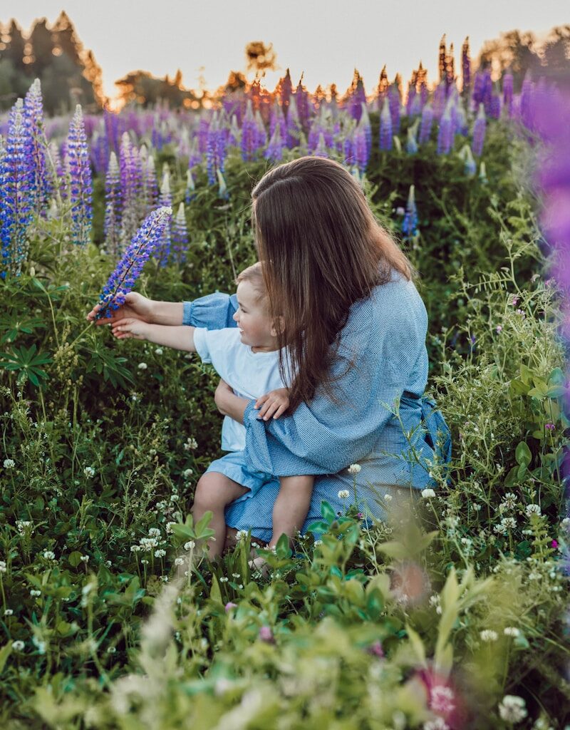 woman sitting with baby on her lap surrounded with purples flower