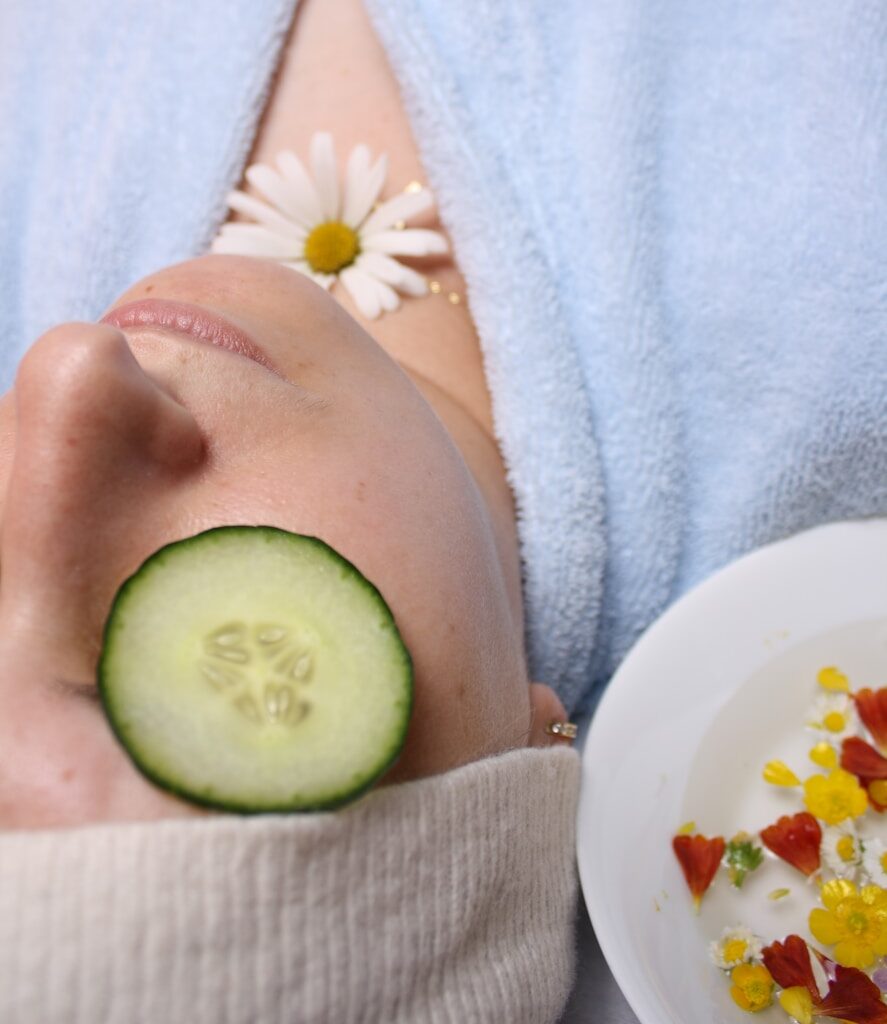 woman wearing blue robe lying with cucumber on eye