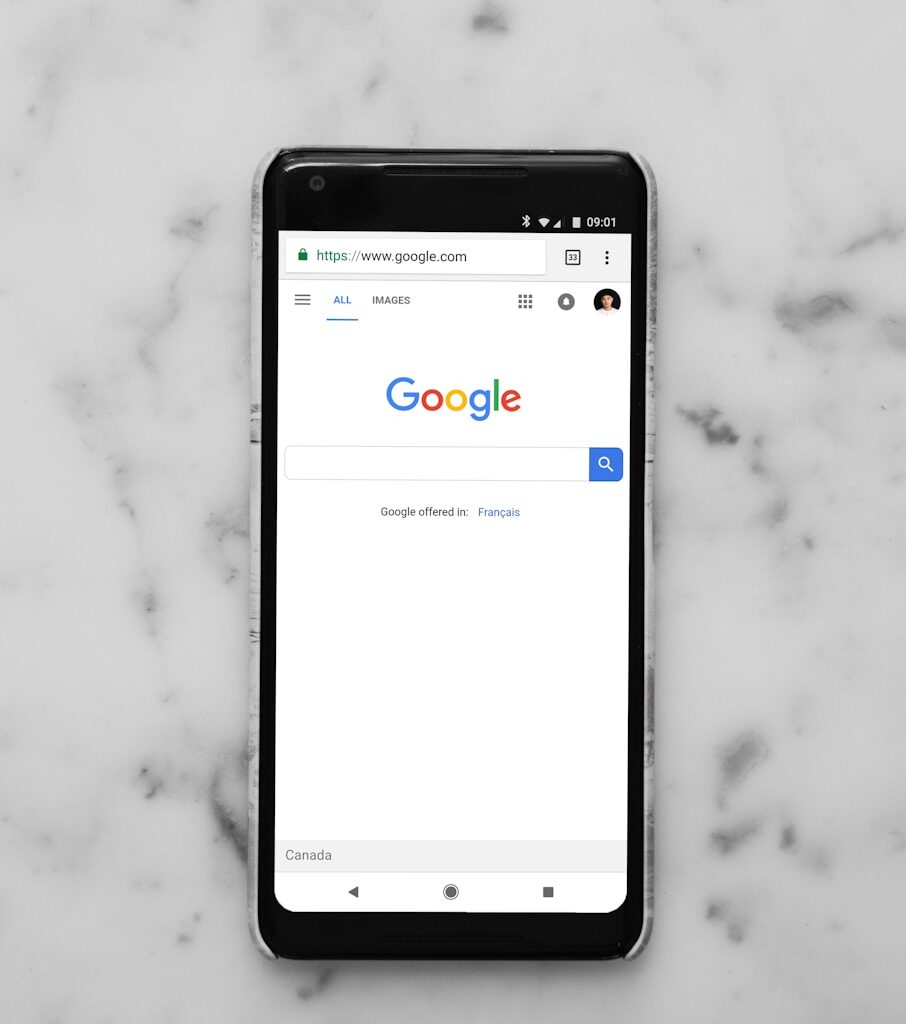 black Android smartphone showing google site on white surface