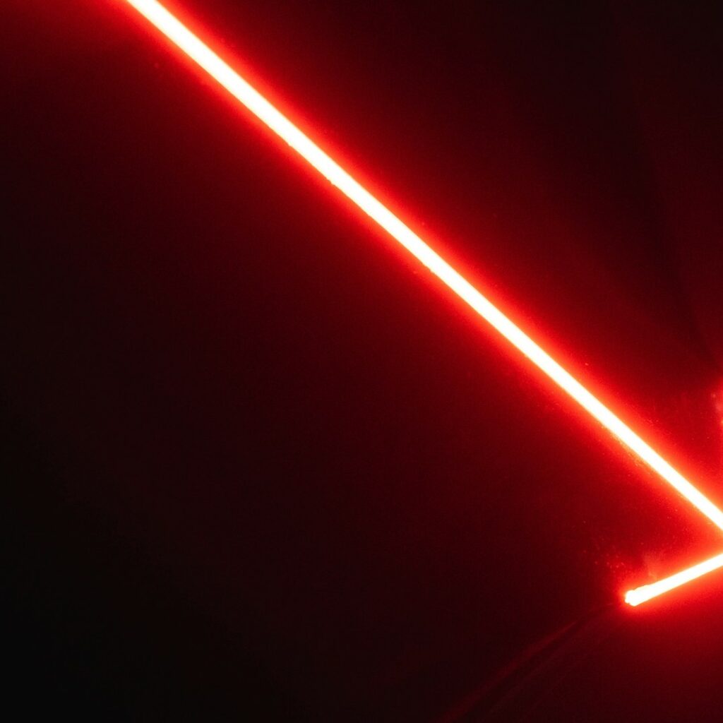 a red neon arrow pointing upward in the dark