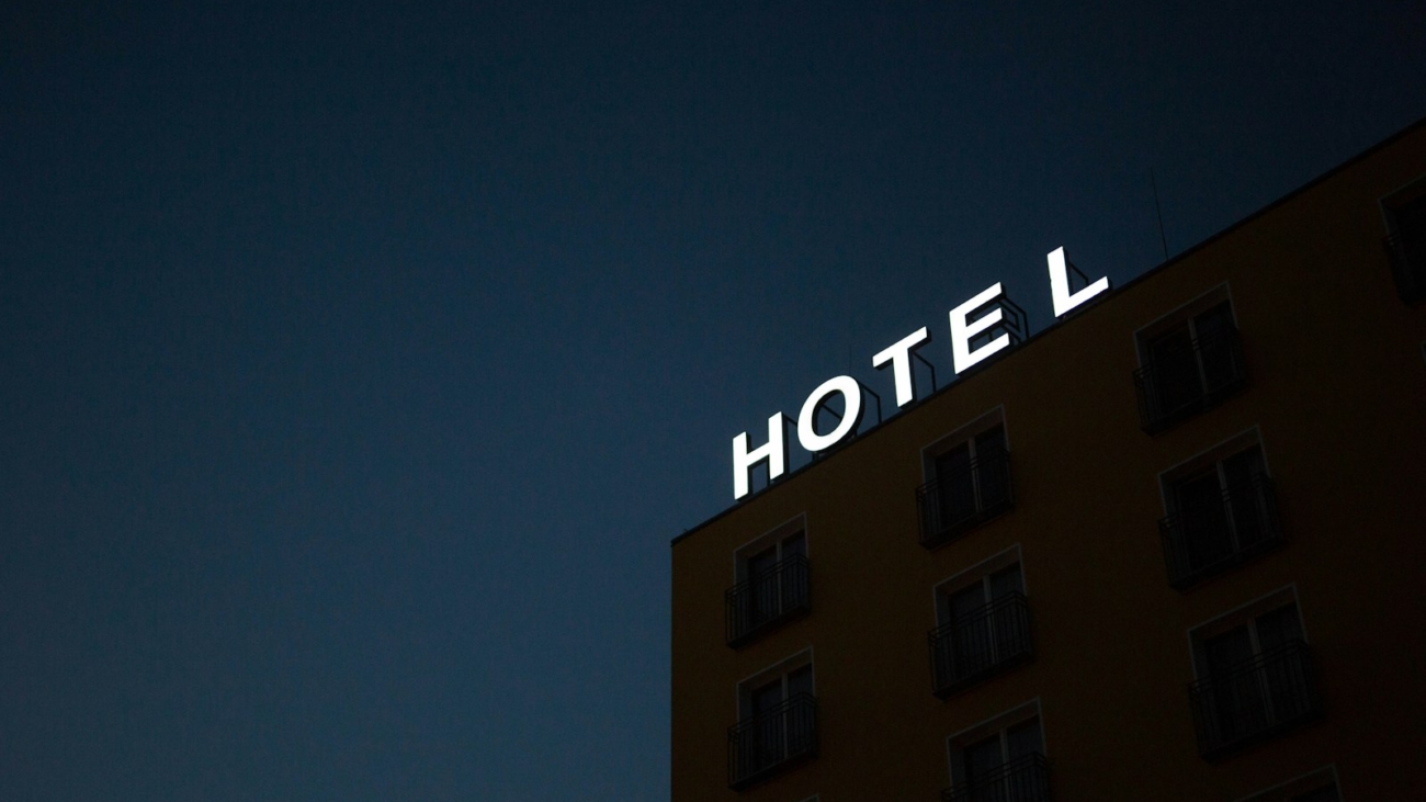 low-angle photo of Hotel lighted signage on top of brown building during nighttime