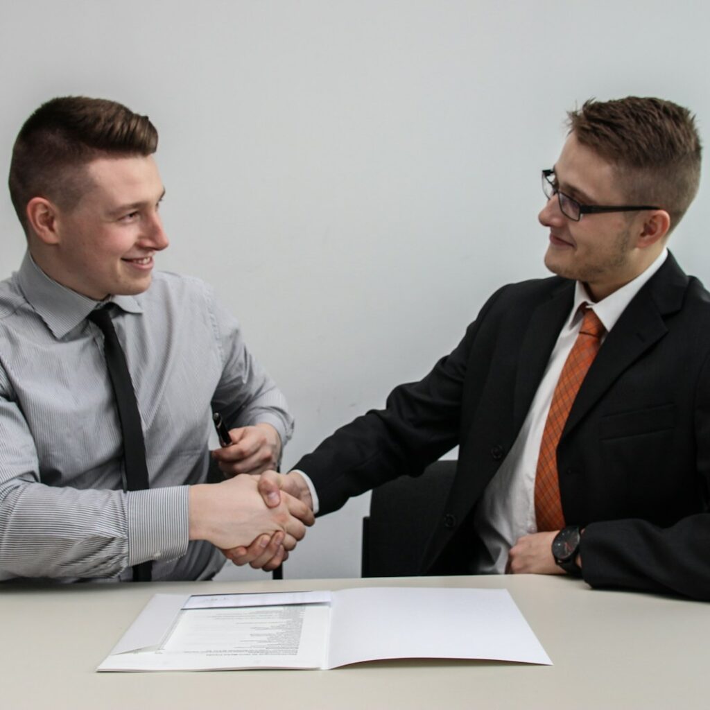 two men facing each other while shake hands and smiling