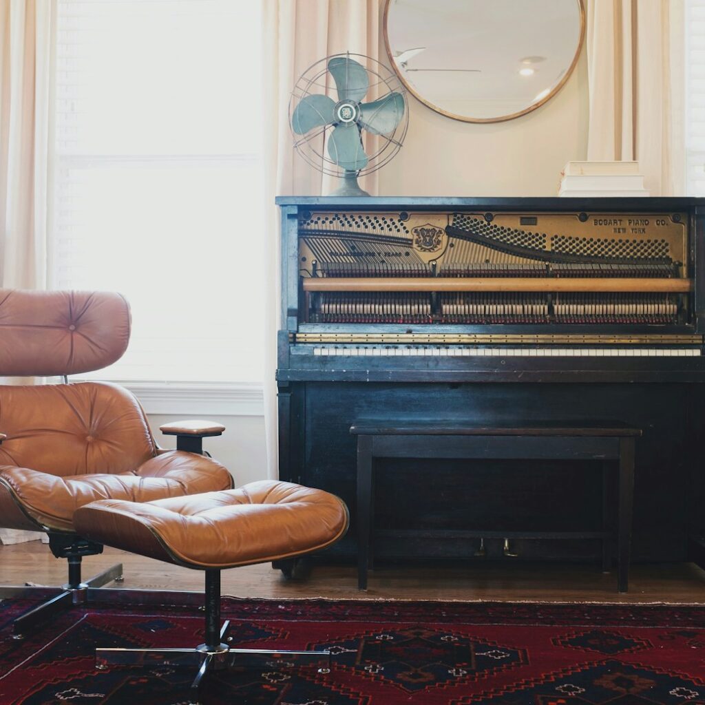 black upright piano near brown leather padded chair