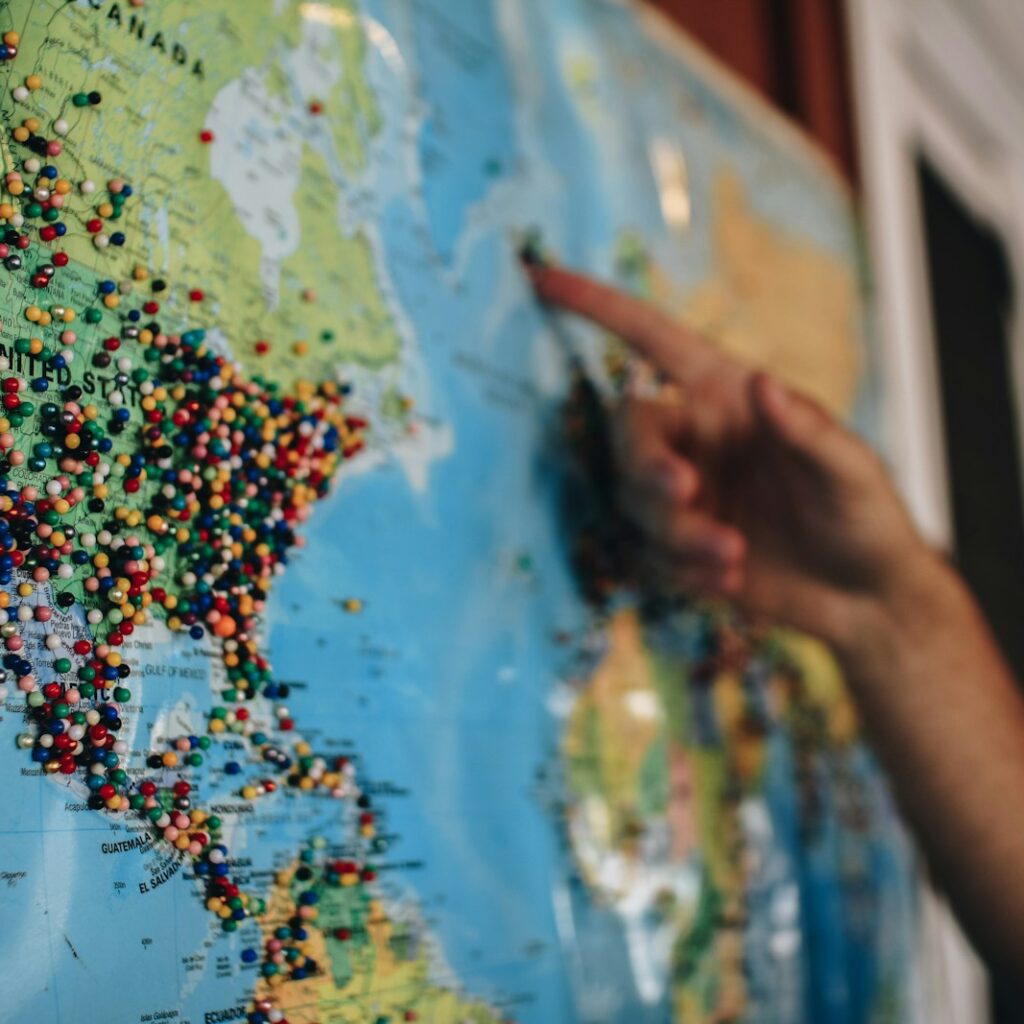 a person pointing at a map with pins on it