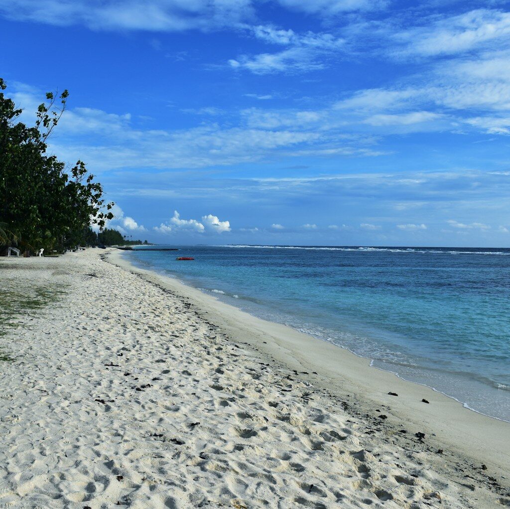 a sandy beach with clear blue water on a sunny day