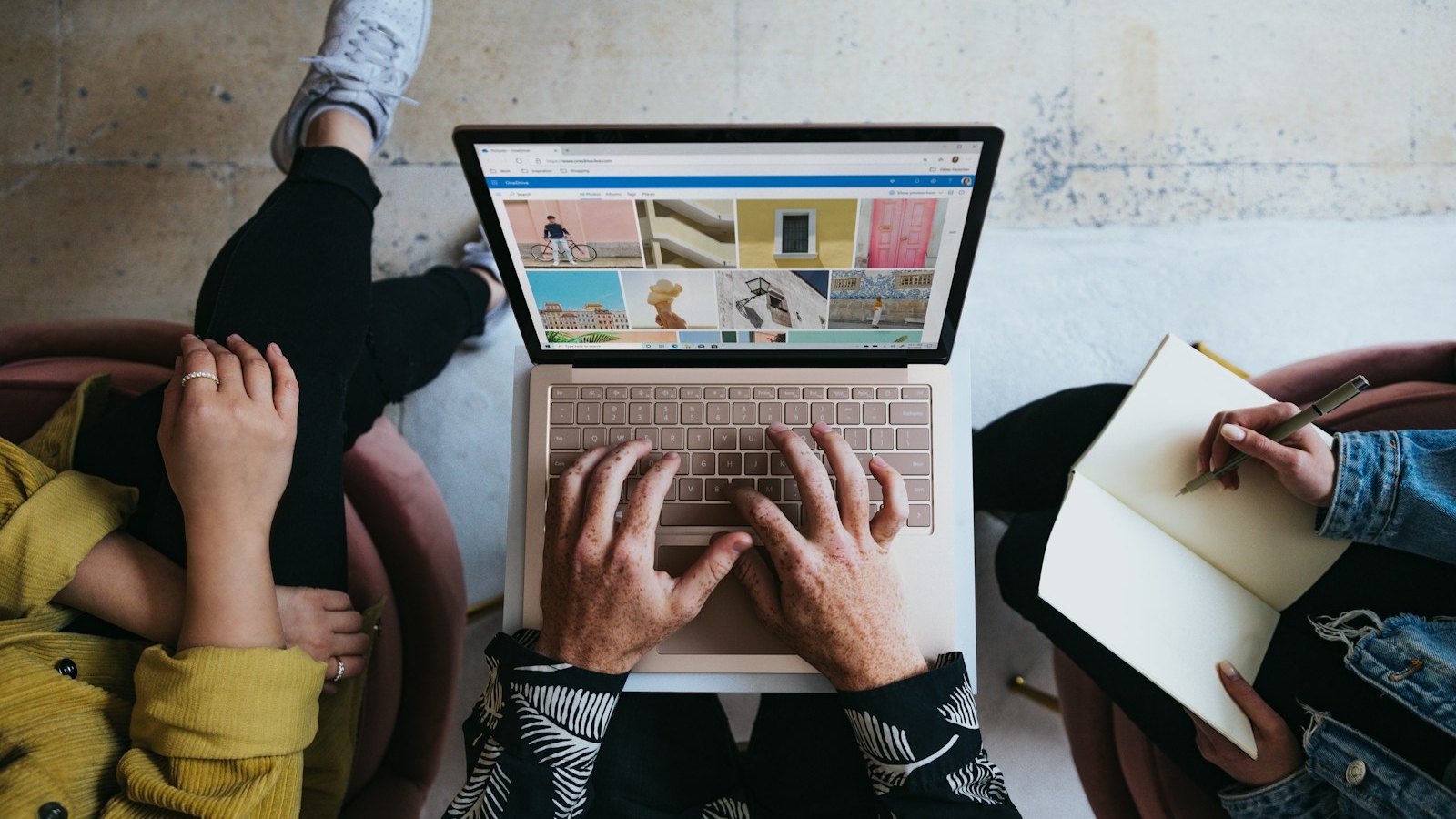 person using microsoft surface laptop on lap with two other people